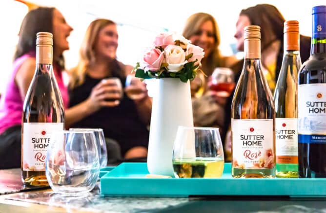 4 women with glasses of wine and some bottles of wine on a table