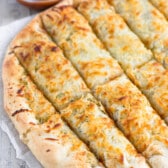 cut breadsticks on parchment with yeast and sauce behind