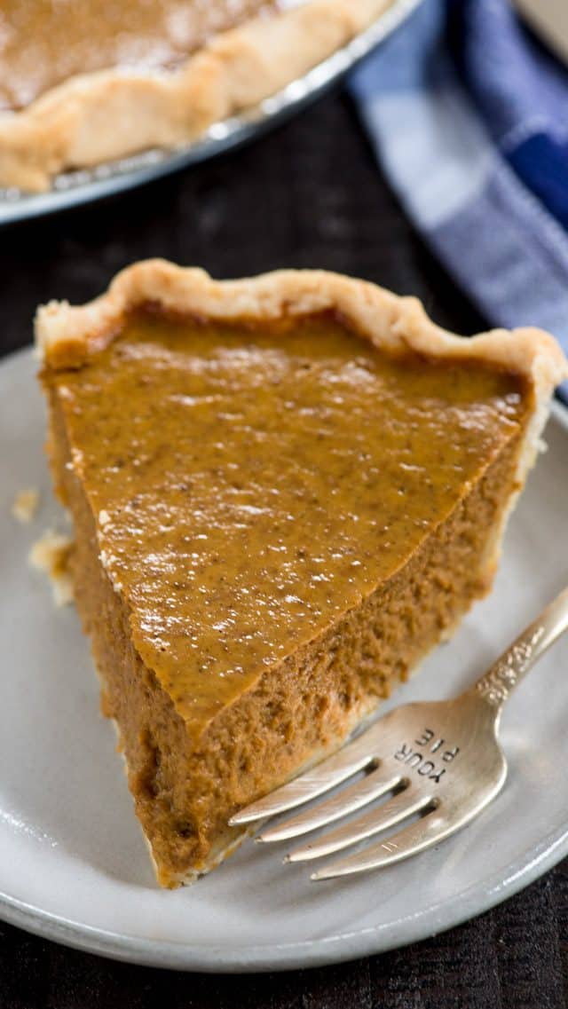 slice of pumpkin pie on a white plate with a fork