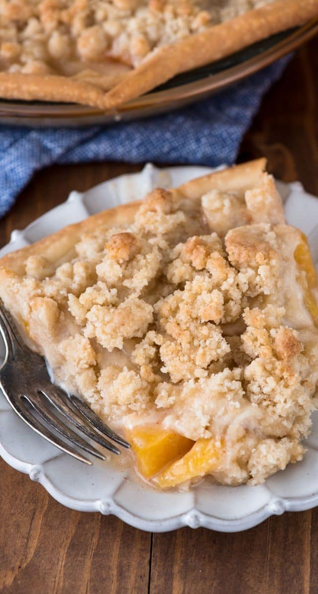 slice of peach crumble pie on a white plate with a fork