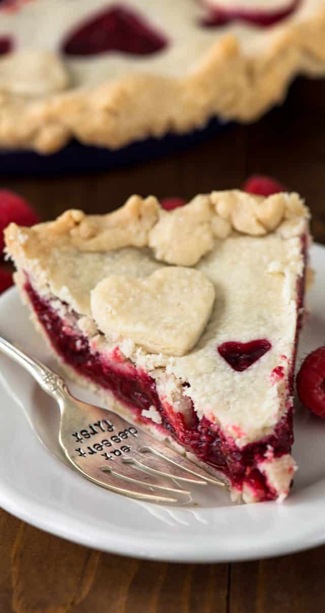 slice of raspberry pie on a white plate with a fork