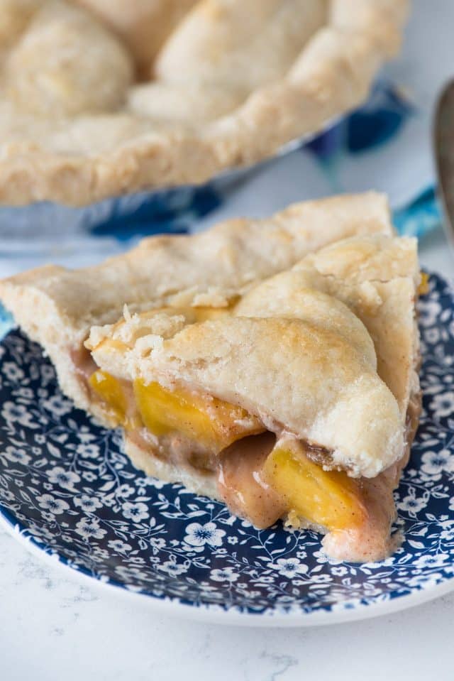 slice of peach pie on a blue and white plate