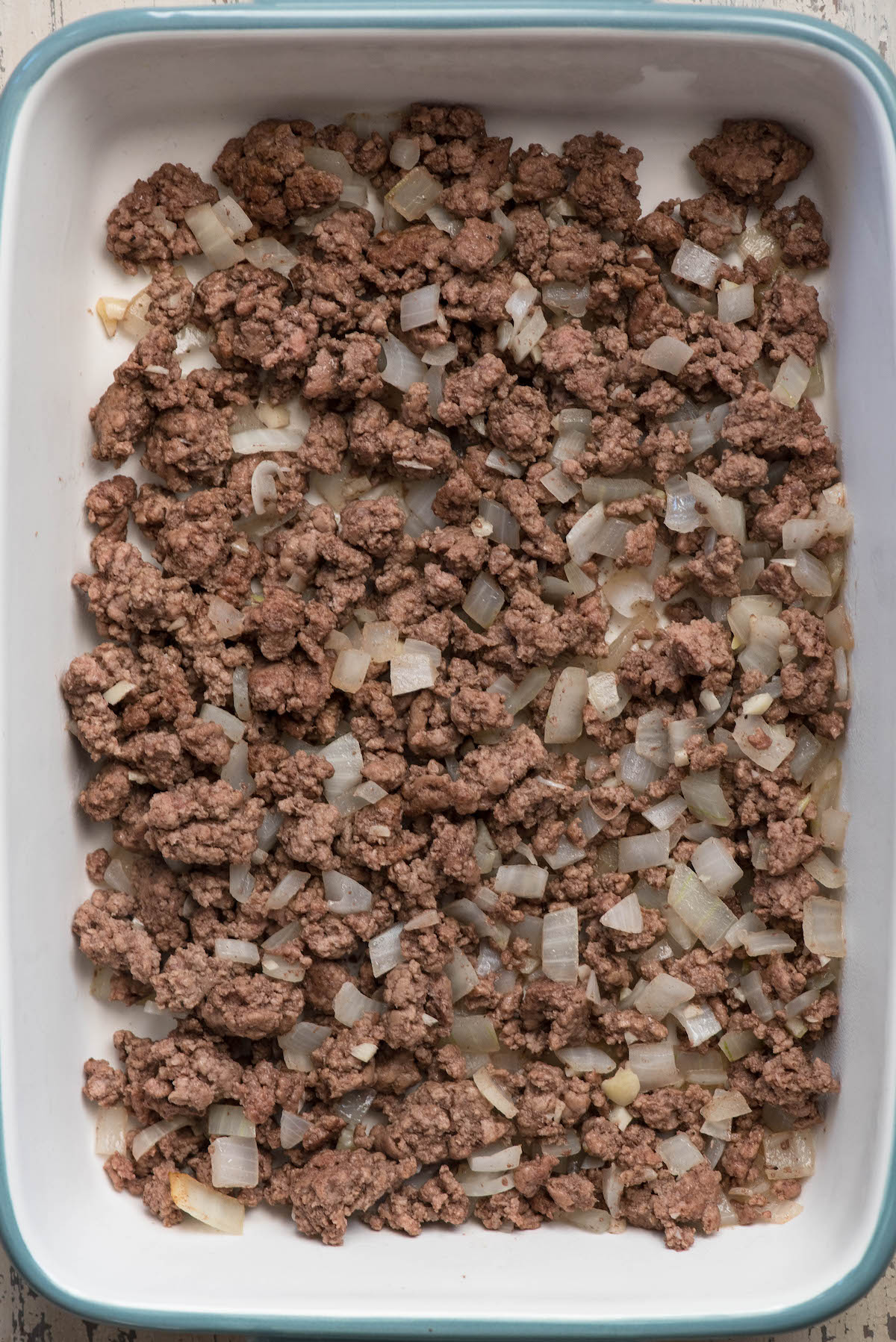 9 by 13 pan with ground beef and onions in the bottom