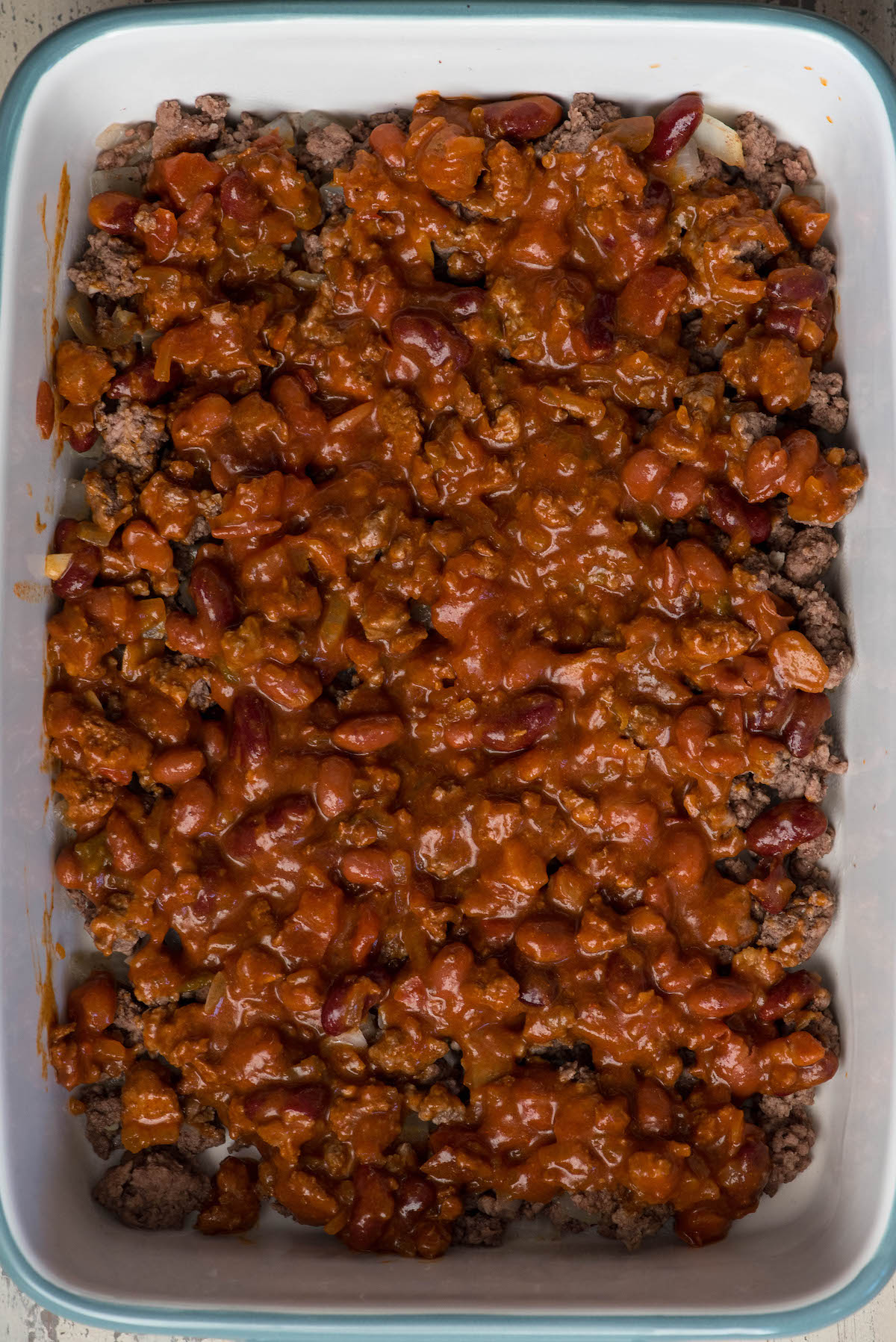 9 by 13 pan with ground beef and chili in the bottom