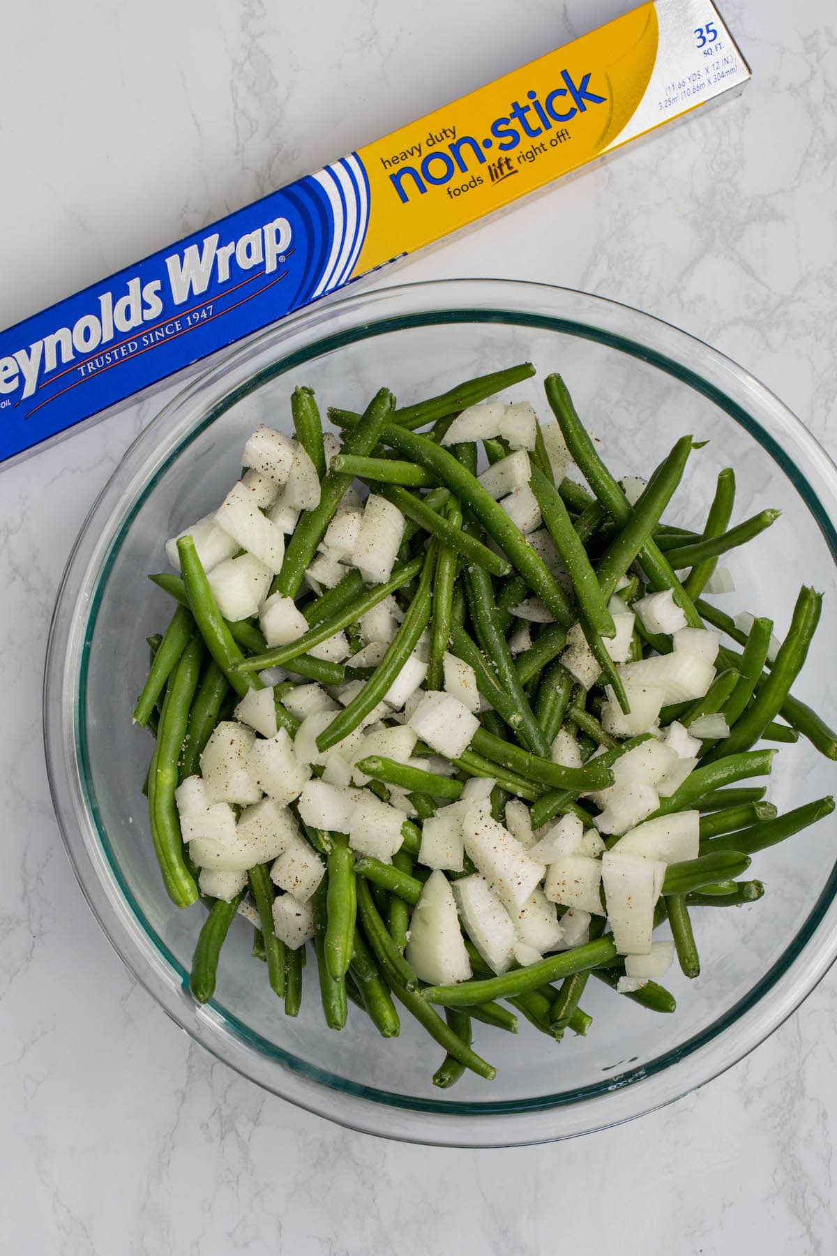 bowl of green beans and onions with foil box