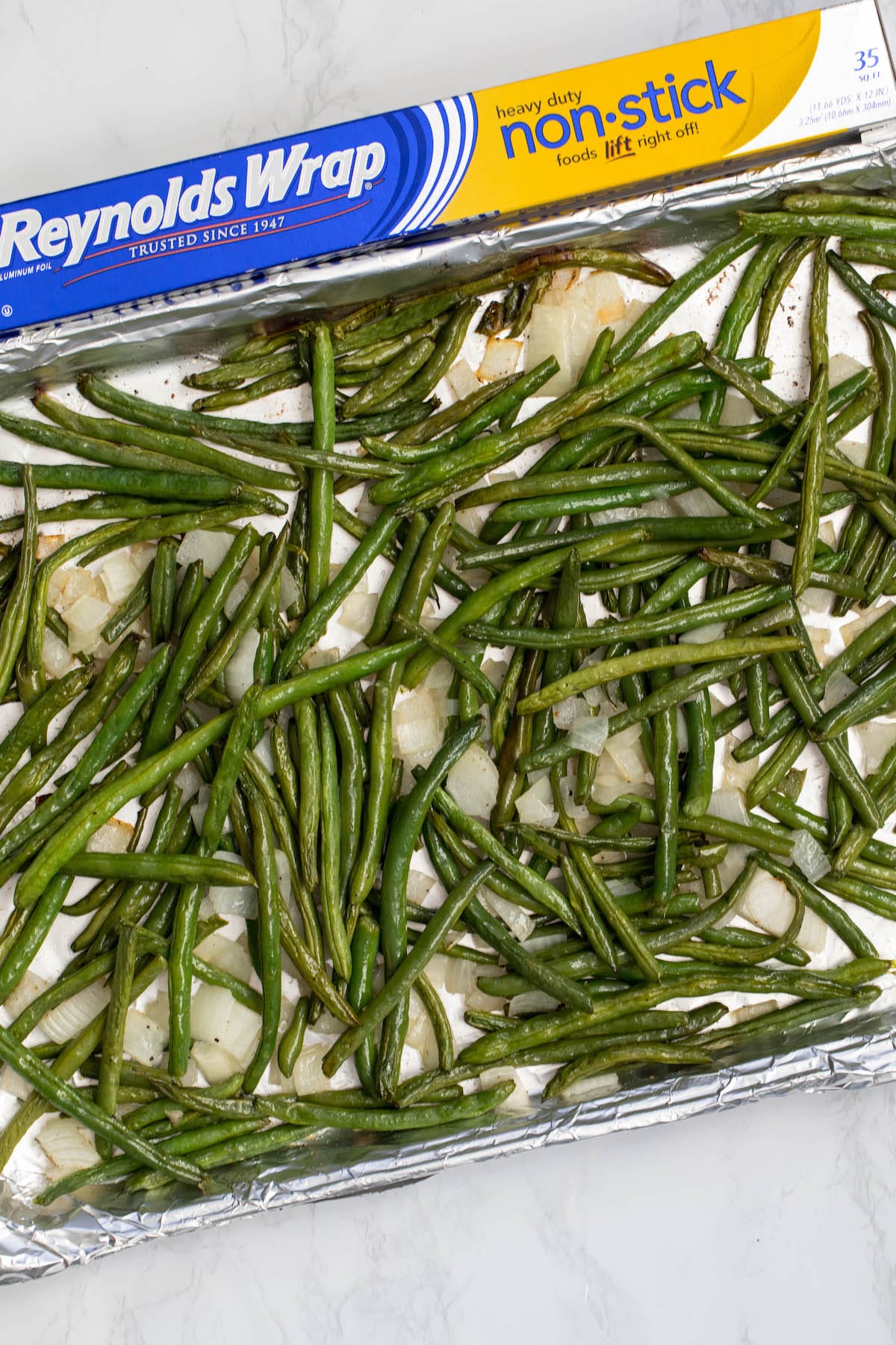 baked green beans and onions on a cookie sheet with foil