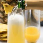 pouring champagne into pineapple mimosa