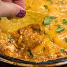 tortilla chip scooping chili cheese dip