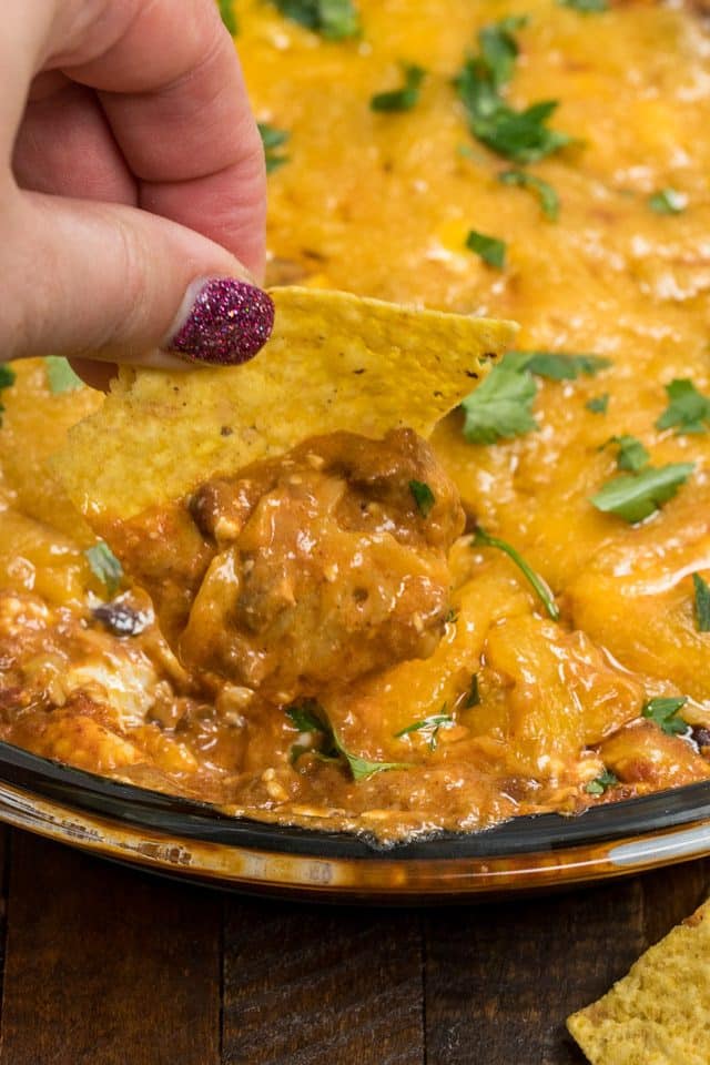 tortilla chip scooping chili cheese dip