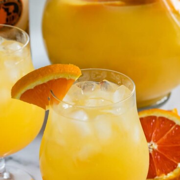 orange vodka party punch in glass and pitcher
