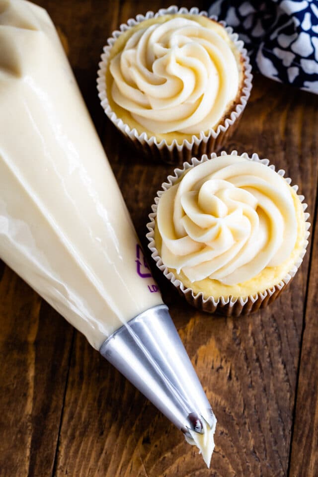 cream cheese on cupcakes with piping bag