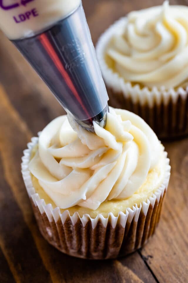 cupcake being frosted with cream cheese frosting