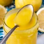 Tall jar of lemon curd with spoon resting on top