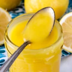 Tall jar of lemon curd with spoon resting on top