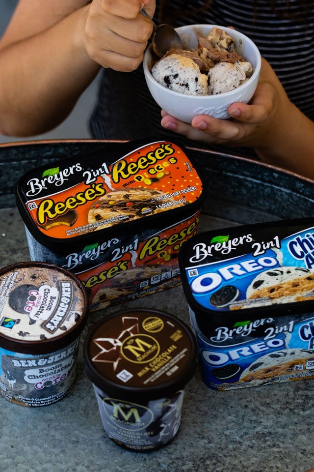 girl holding bowl of ice cream with cartons on table