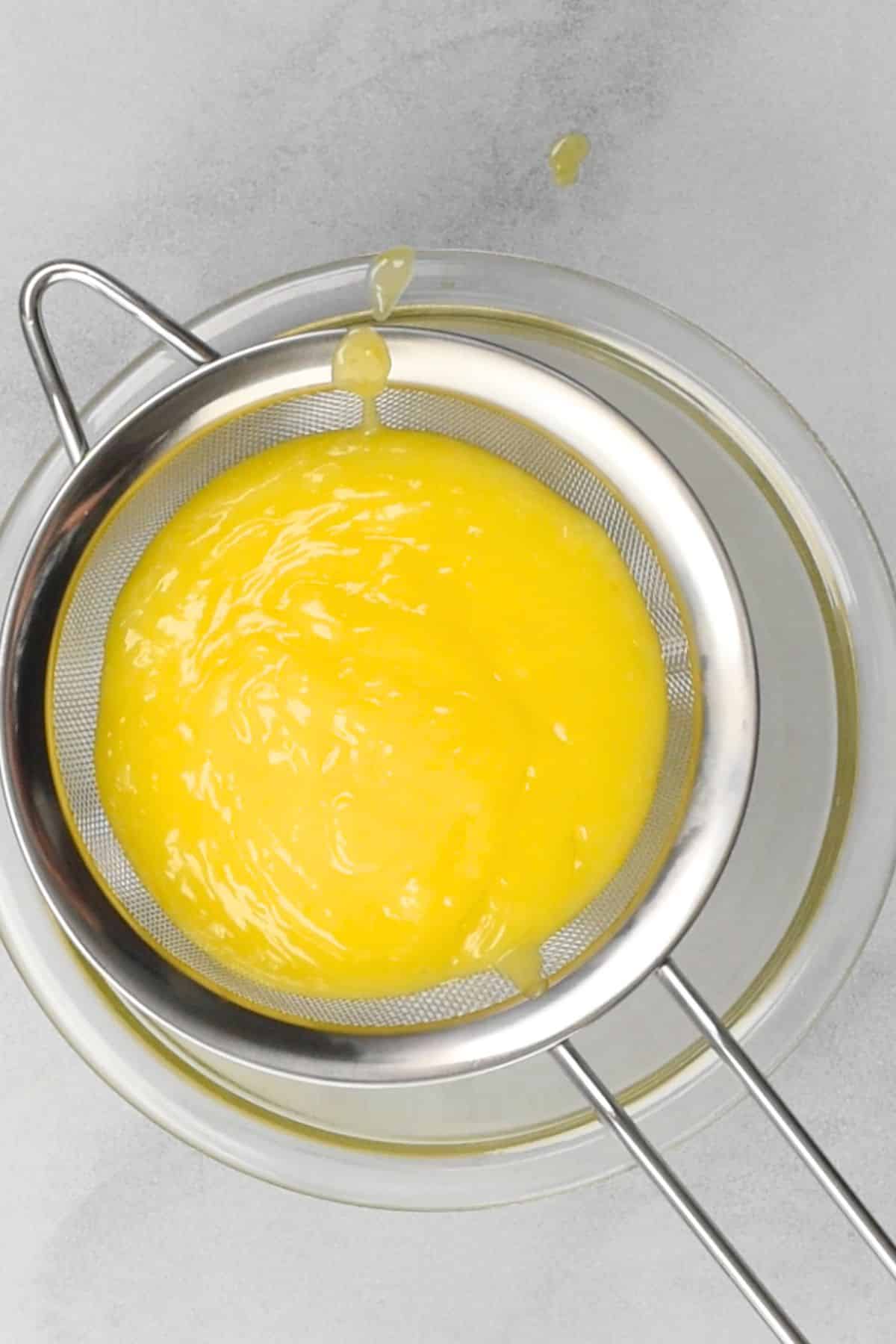 lemon curd in strainer over bowl.