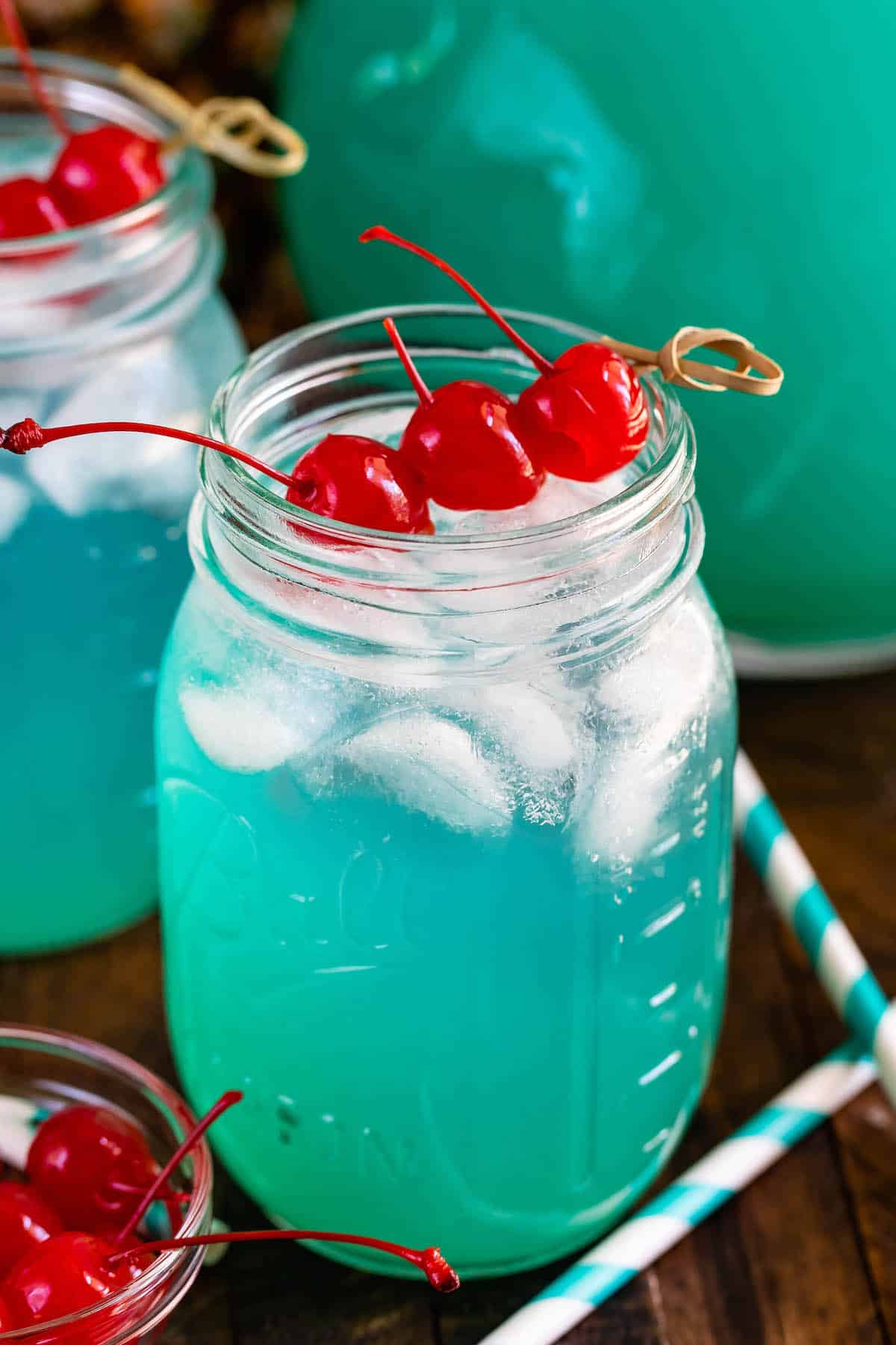 jar of blue drink with 3 cherries.