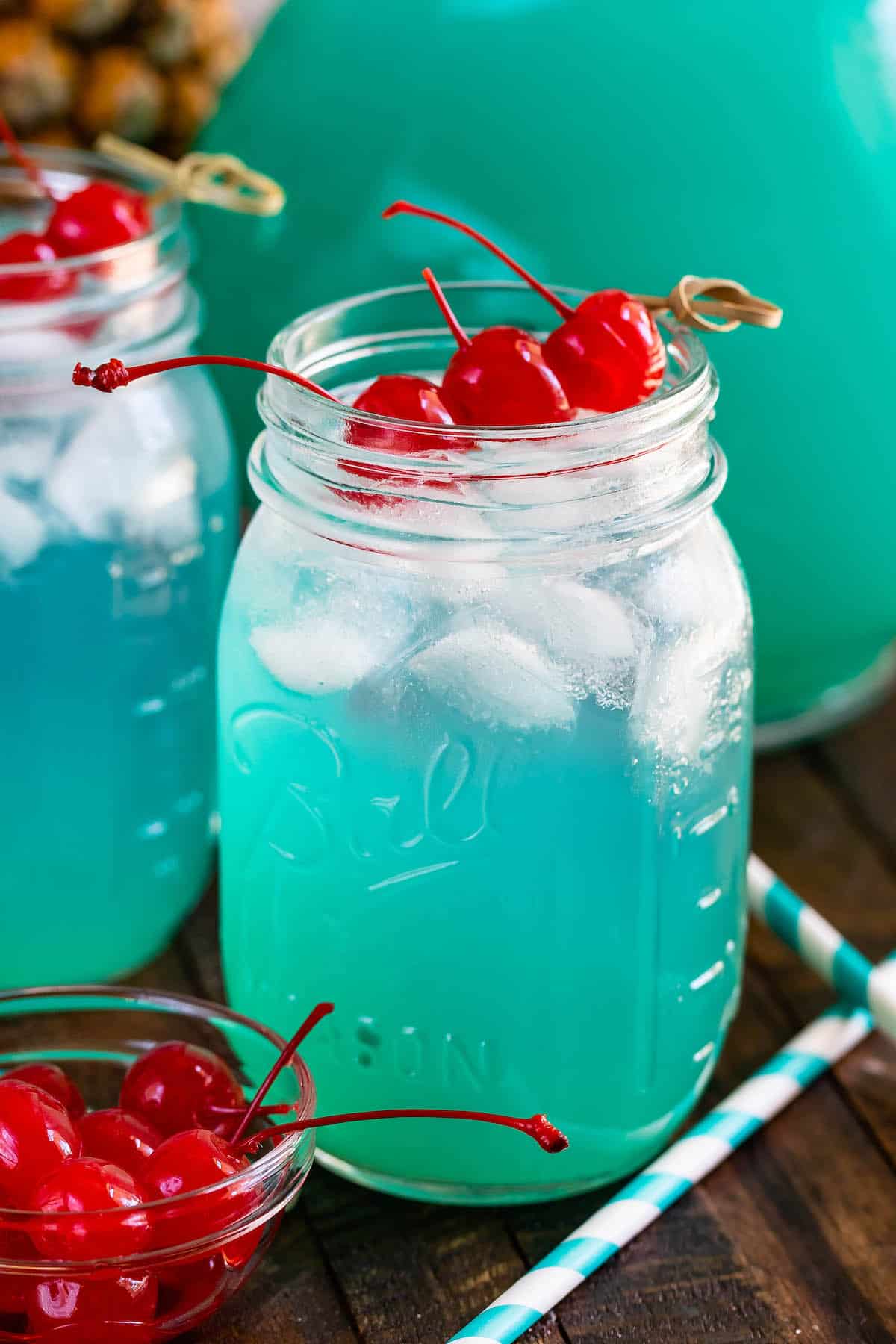 jar of blue drink with 3 cherries.