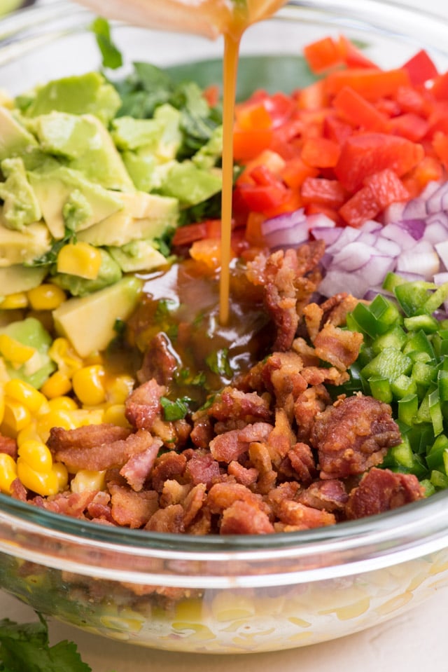 corn salad with dressing being poured on