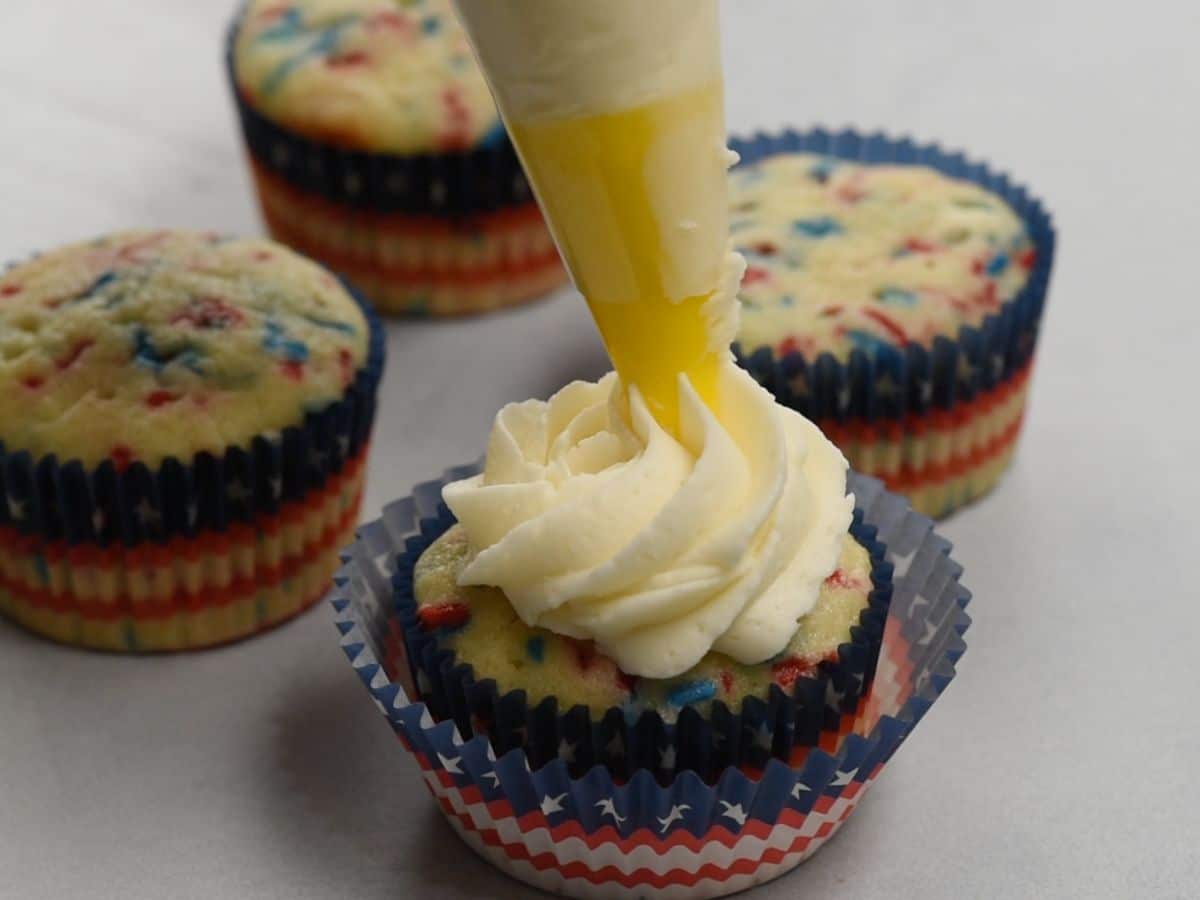 frosting a cupcake with vanilla frosting.