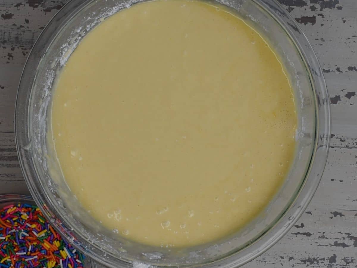 funfetti cake batter in glass bowl with hand mixer.