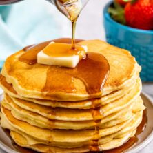 stack of pancakes with butter and syrup being poured over them
