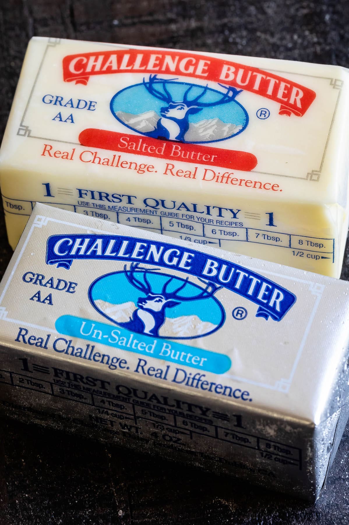 stick of unsalted butter and stick of salted butter on dark background.