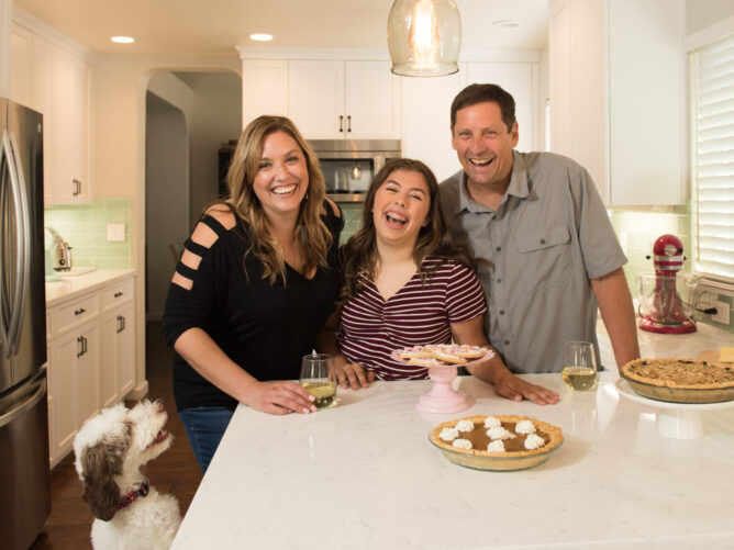 family in kitchen laughing with dog