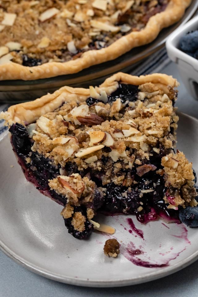 slice of blueberry crumble pie with bite missing