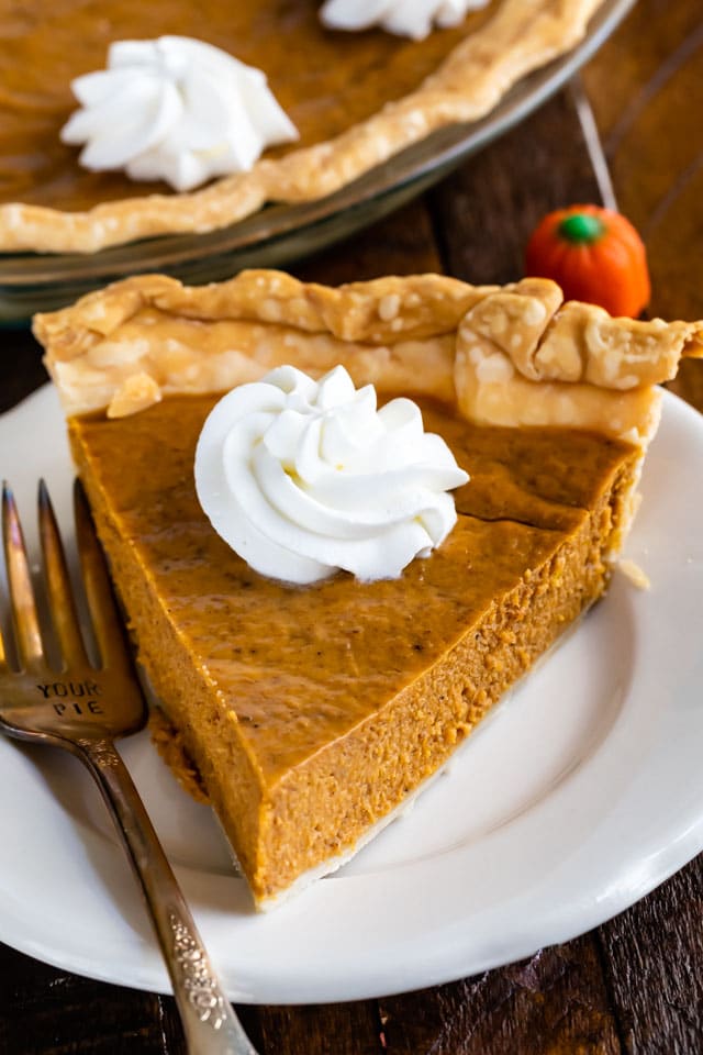 slice of pumpkin pie on white plate with whipped cream