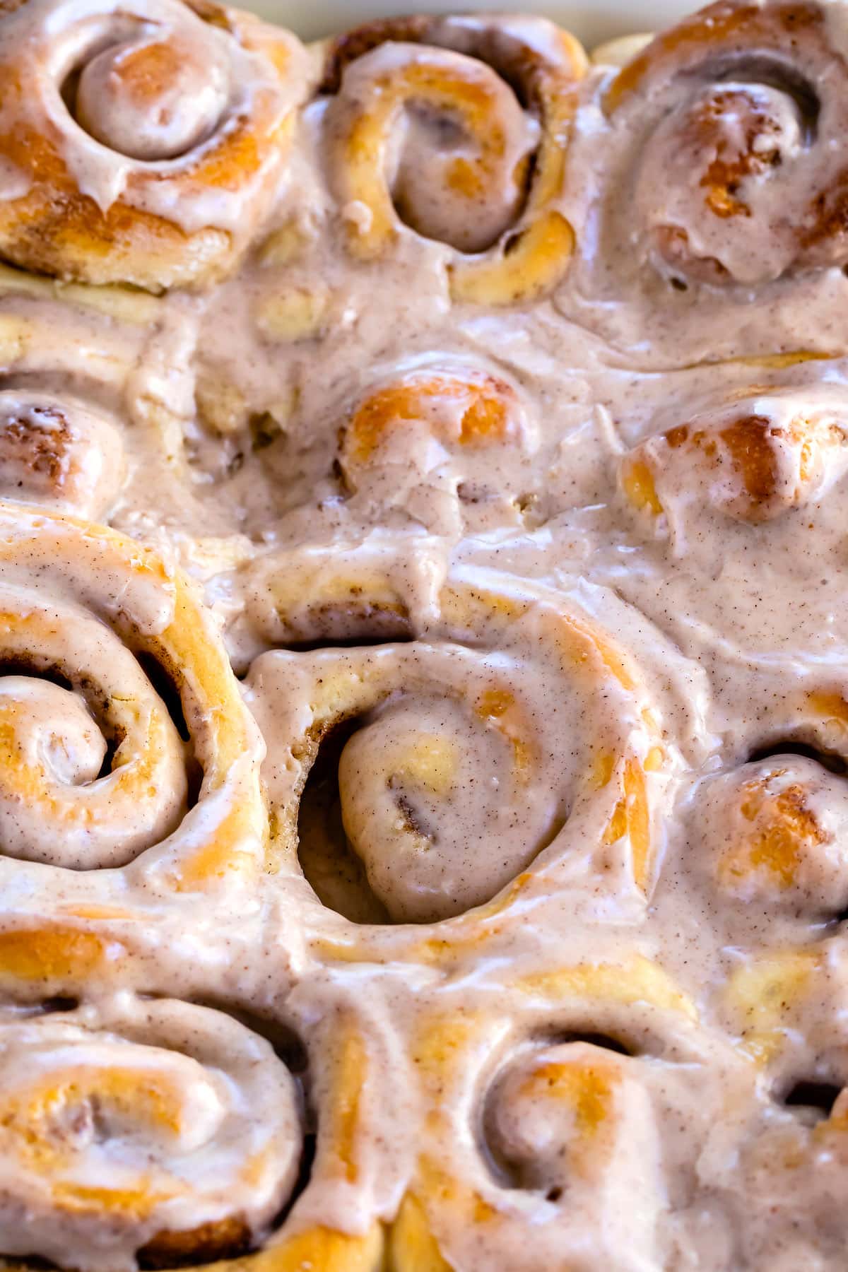 close up of pan of cinnamon rolls with icing