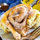 cinnamon roll on white plate with blue napkin behind and fork