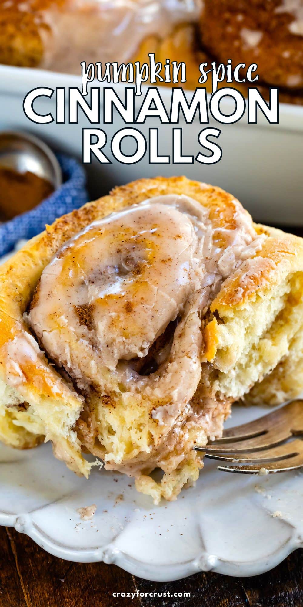 cinnamon roll on white plate with blue napkin behind and fork