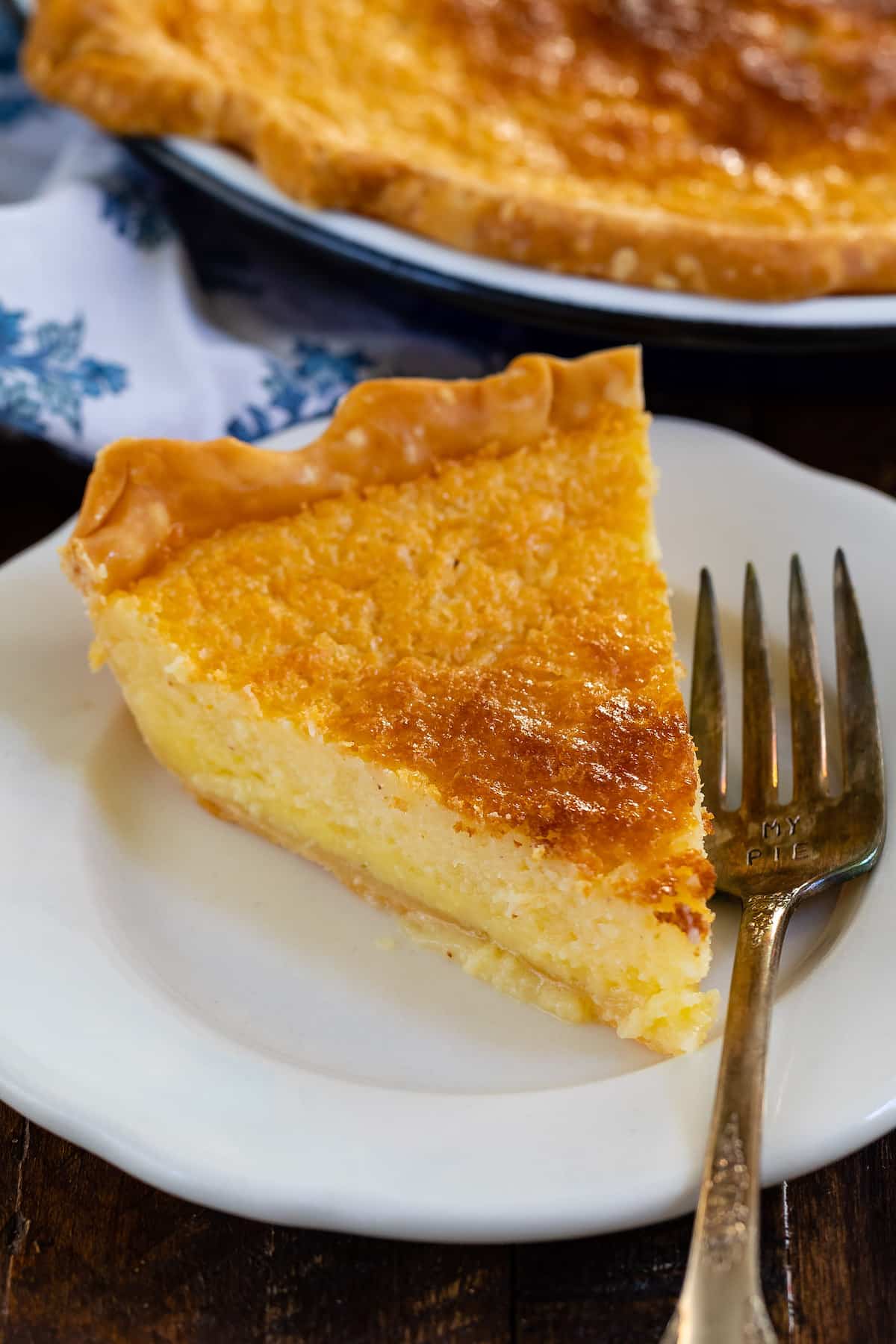 slice of pie on white plate with fork and pie behind