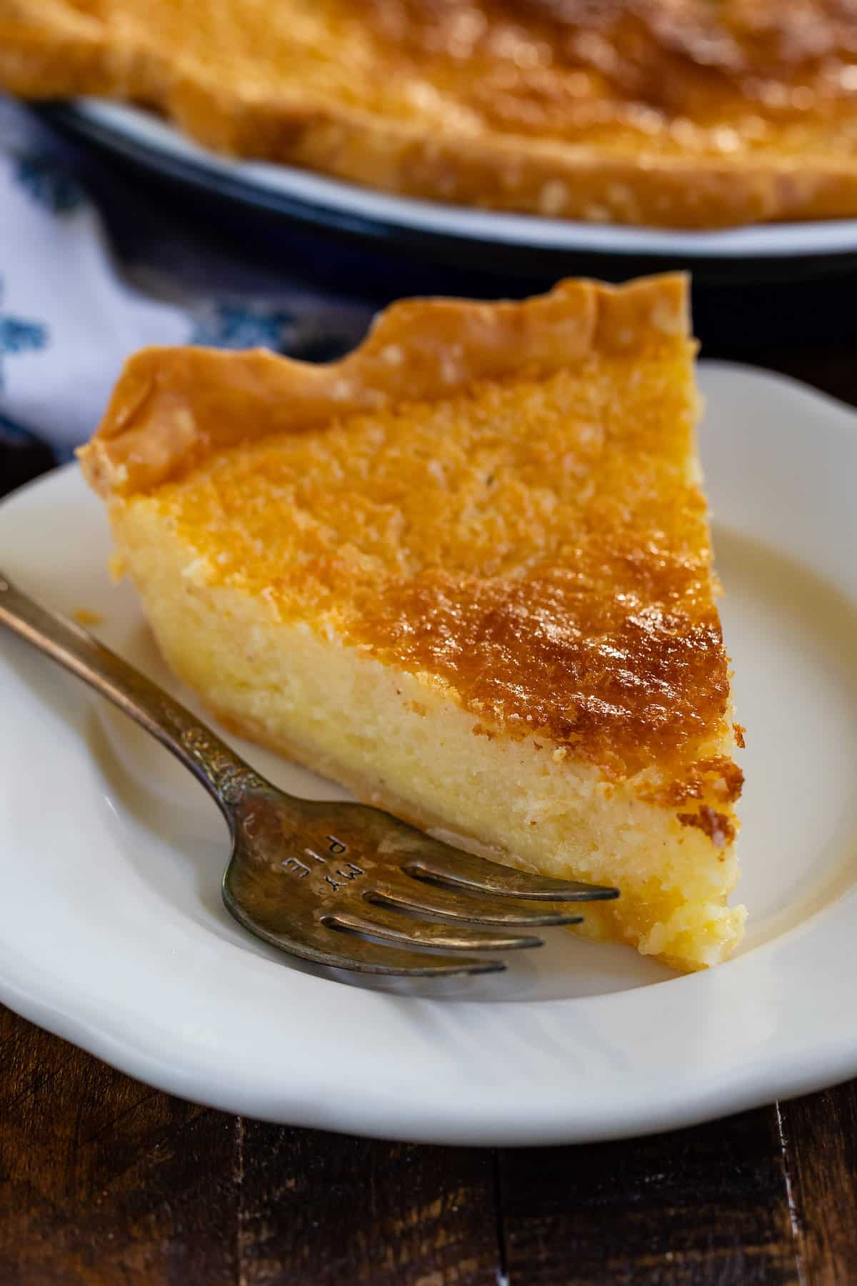 slice of pie on white plate with fork and pie behind