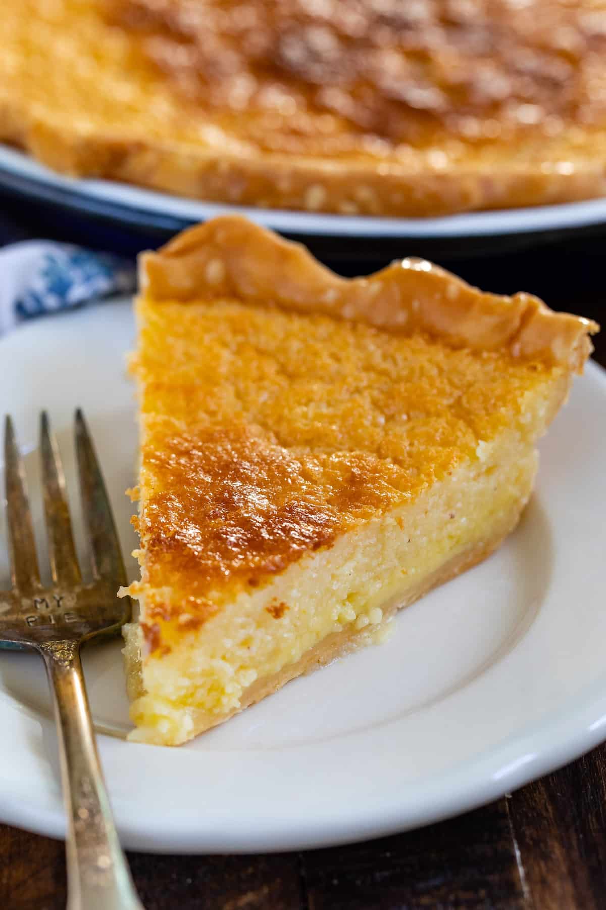 slice of pie on white plate with fork and pie behind