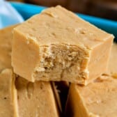 pile of fudge squares in teal container with fudge behind