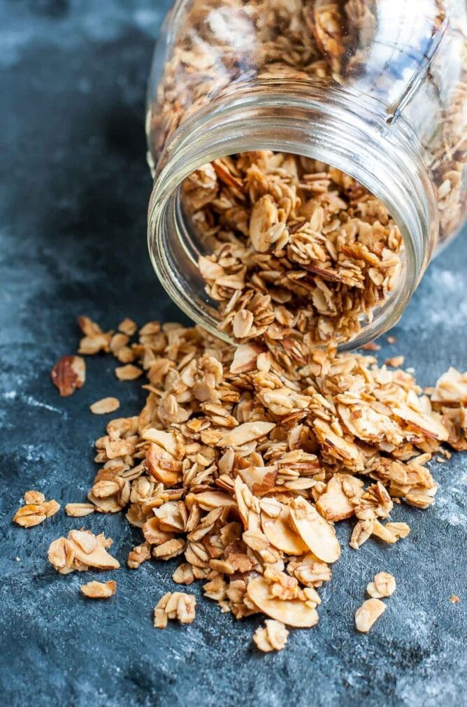 Granola spilling out of a glass jar on a blue napkin