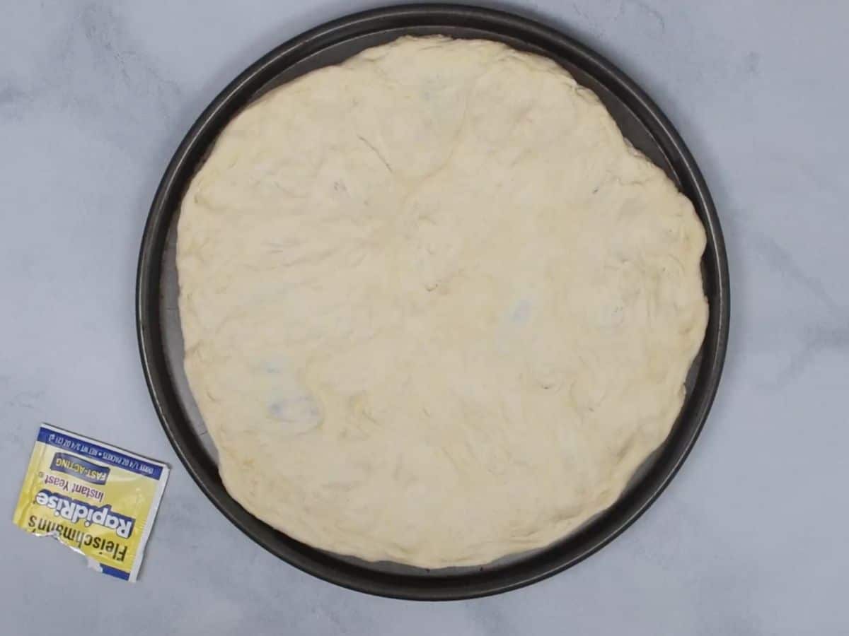 stretched out pizza dough on pizza pan.