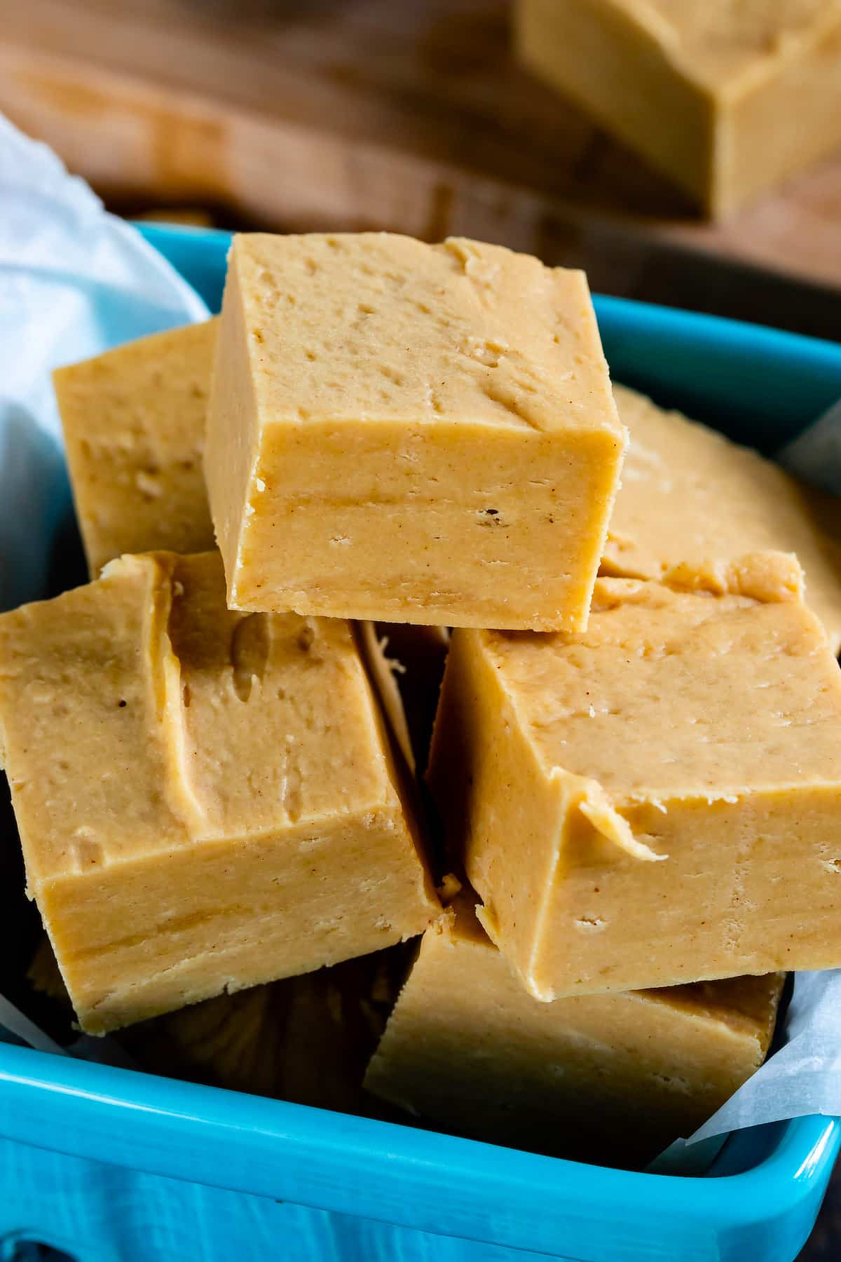 pile of fudge squares in teal container with fudge behind