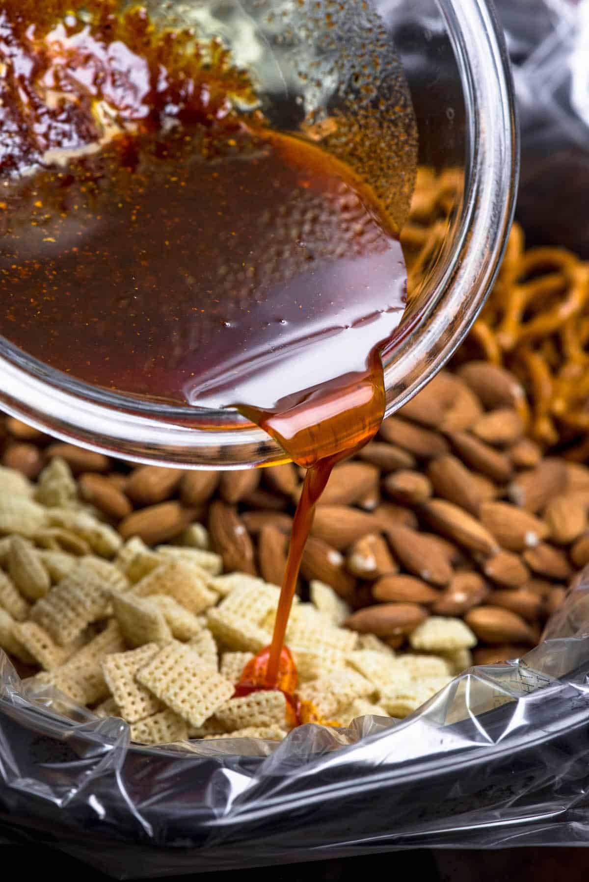 bowl pouring sauce on Chex mix