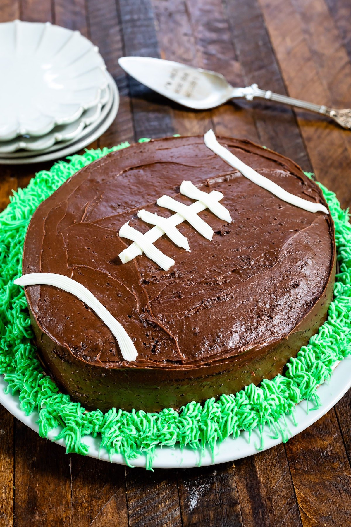cake on plate decorated like football with green frosting like grass on wood background