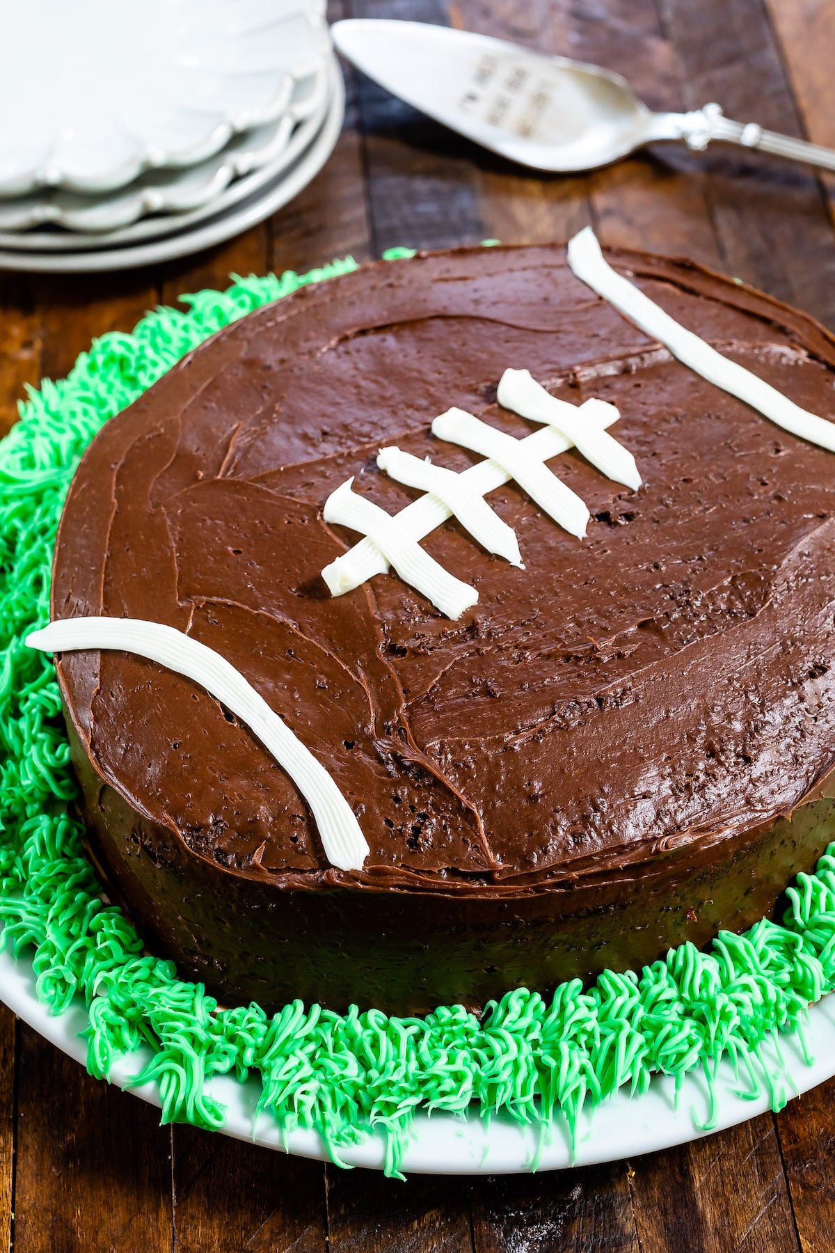 cake on plate decorated like football with green frosting like grass on wood background