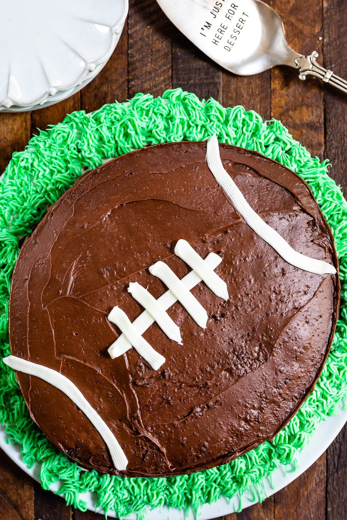 cake on plate decorated like football with green frosting like grass on wood background