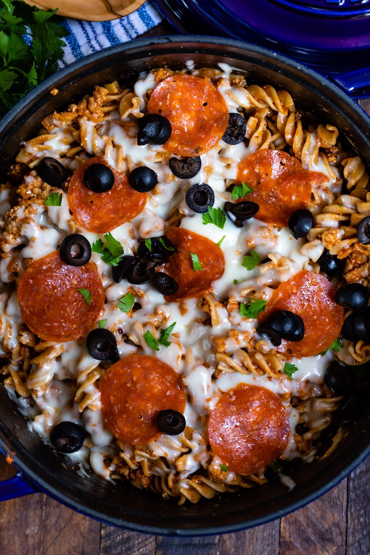 overhead photo showing pasta in blue pot with pizza toppings