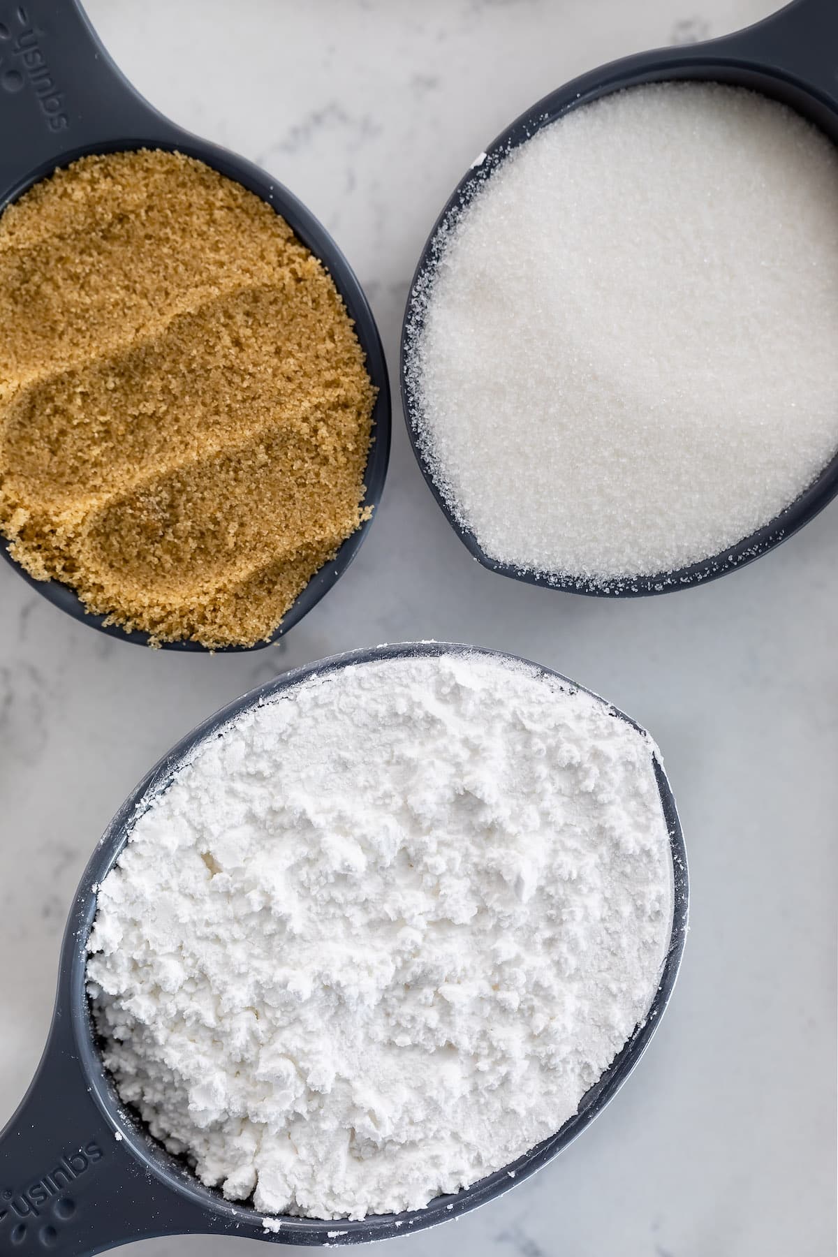 measuring cups with brown, granulated and powdered sugar