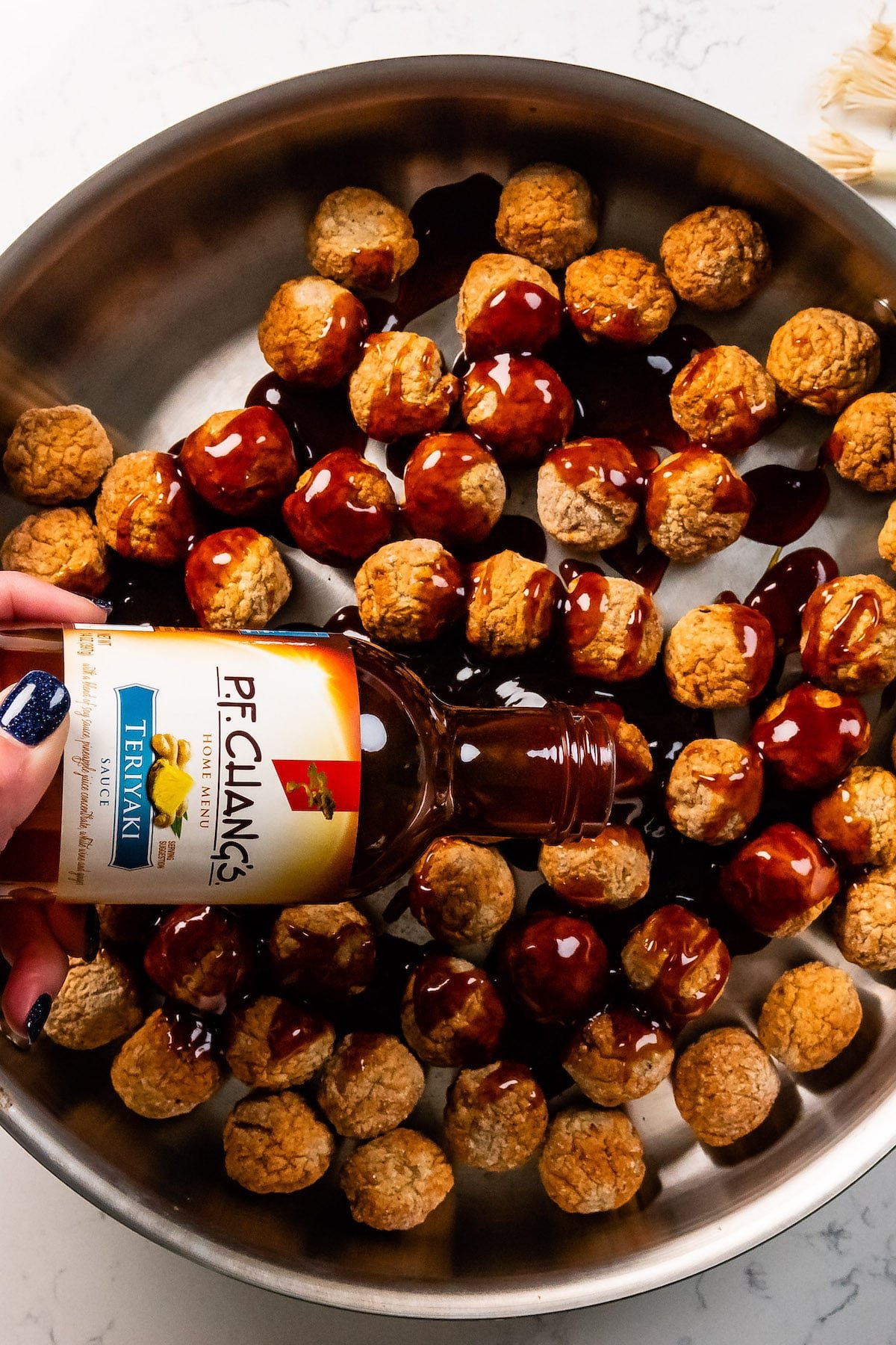 sauce pouring over meatballs in pan