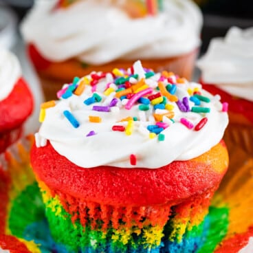 rainbow cupcake with white frosting and sprinkles.