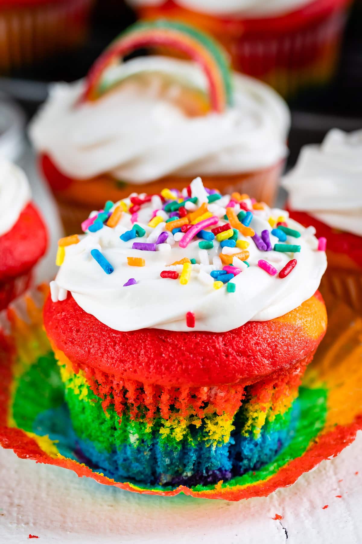 rainbow cupcake with white frosting and sprinkles.