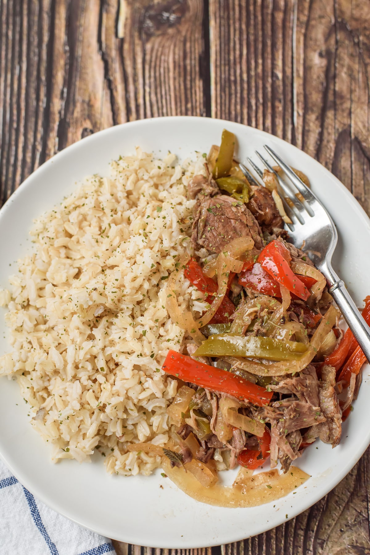 peppers and steak on white plate with rice and fork